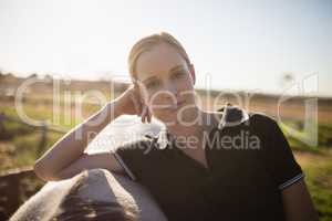 Confident female jockey standing by horse at barn