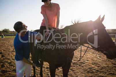 Male trainer adjusting young woman leg on stirrup