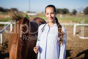 Confident vet standing by horse at barn