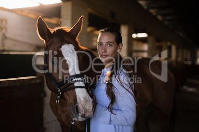 Confident female vet standing by horse in stable