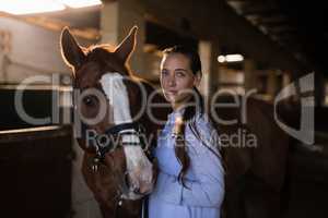 Confident female vet standing by horse in stable