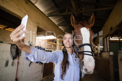 Smiling vet taking selfie with horse in stable