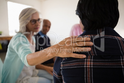 Woman consoling female friend while sitting on chair