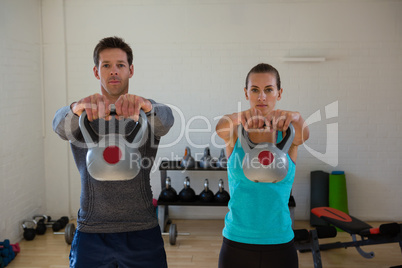 Portrait of confident athletes lifting kettlebells