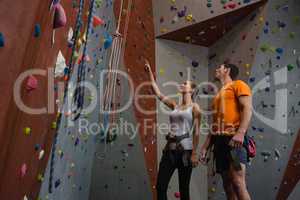 Friends discussing while standing by climbing wall at gym