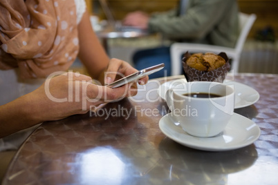 Midsection of woman using mobile phone in cafe