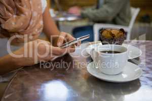 Midsection of woman using mobile phone in cafe