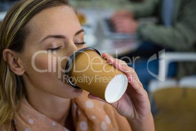 Close up of woman with eyes closed having coffee at cafeteria