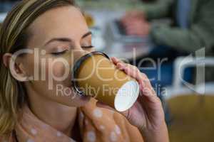 Close up of woman with eyes closed having coffee at cafeteria