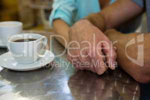 Cropped image of couple holding hands in cafe