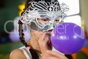 Adorable girl blowing balloon during birthday party