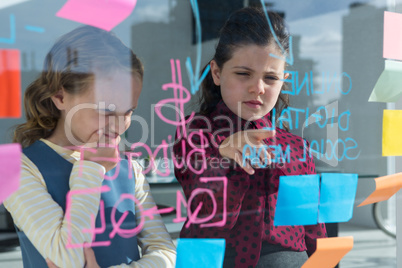 Female coworkers anlayzing data at office seen through glass