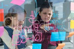 Female coworkers anlayzing data at office seen through glass