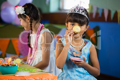 Cute girls having tea at table during birthday party