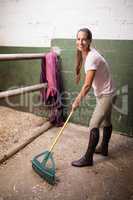 Portrait of female jockey cleaning stable