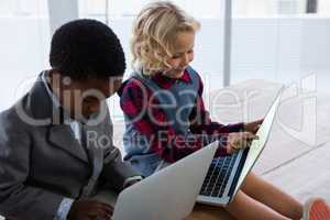 Business people using laptop computers while sitting on wooden table in office