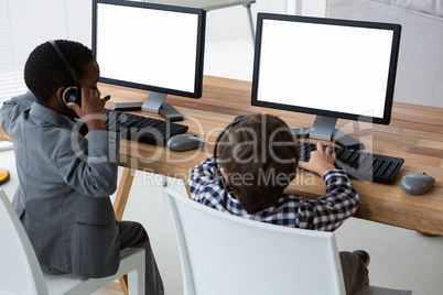 High angle view of male colleagues talking through headset at desk