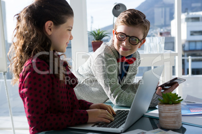 Smiling business people discussing over laptop in office