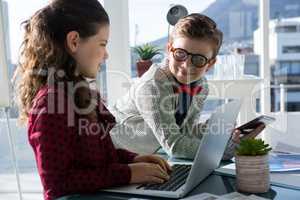 Smiling business people discussing over laptop in office