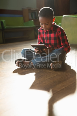 Boy sitting on wooden floor using digital tablet