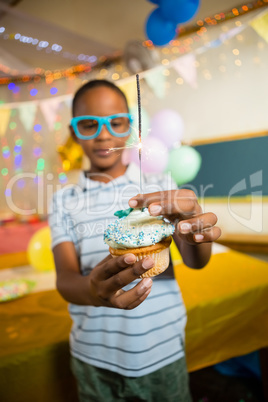 Cute boy decorating cupcake with sparkler during birthday party