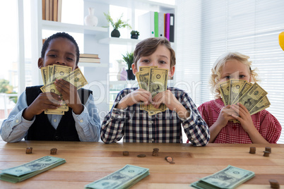 Portrait of business people with currency standing at table in office