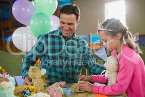 Father and girl playing toy kitchen set