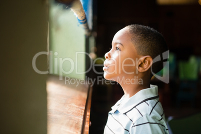 Thoughtful boy looking through window