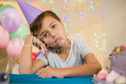 Boy sitting near a birthday cake at home