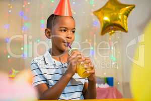 Thoughtful boy drinking juice during birthday party