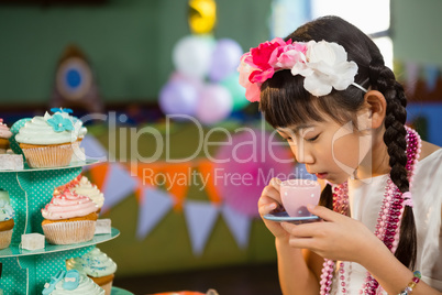 Cute girl drinking tea during birthday party