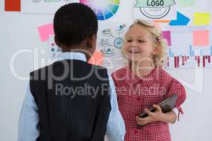 Business people discussing while standing by whiteboard in office