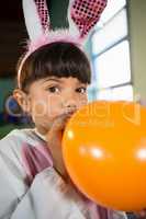 Girl blowing balloon during birthday party at home