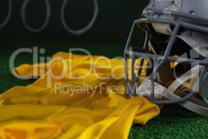 Close-up of American football head gear and jersey lying on artificial turf