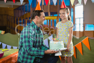 Father giving surprised birthday cake to her daughter