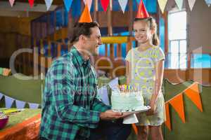 Father giving surprised birthday cake to her daughter