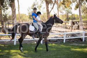 Side view of female jockey teaching horseback riding to girl