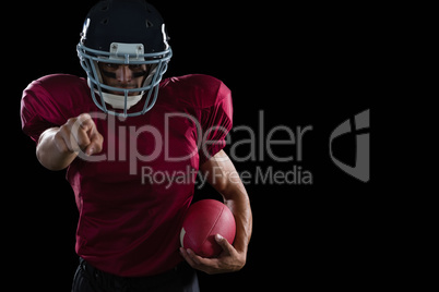 American football player pointing holding a ball in other hand