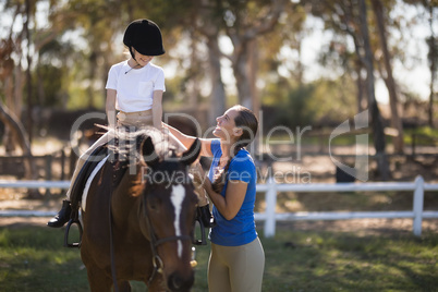 Side view of happy female jockey teaching girl