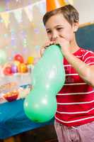 Cute boy blowing balloon during birthday party