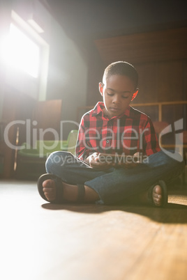 Boy sitting on wooden floor using digital tablet