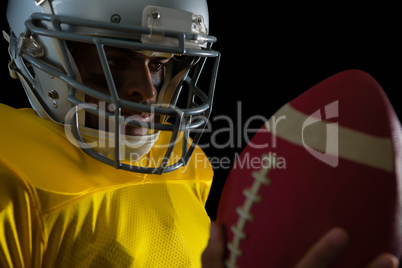 American football player looking at football in his hand