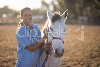 Portrait of smiling female vet examining horse