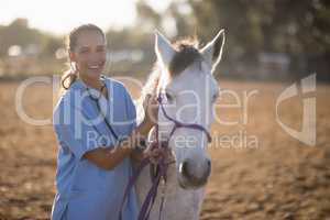 Portrait of smiling female vet examining horse