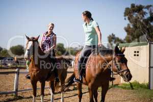 Female friends talking while sitting on horse