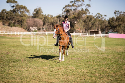 Full length of female jockey horseback riding