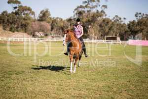 Full length of female jockey horseback riding