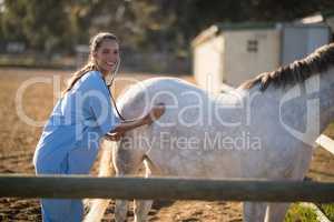 Female vet examining horse at barn
