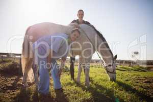 Portrait of jockey and vet standing by horse at barn
