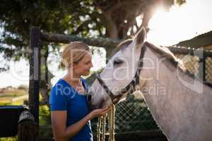 Smiling woman looking at horse at barn